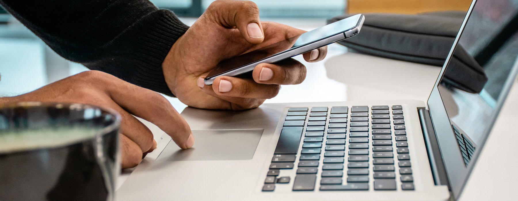 Closeup of a man working on his phone and his laptop